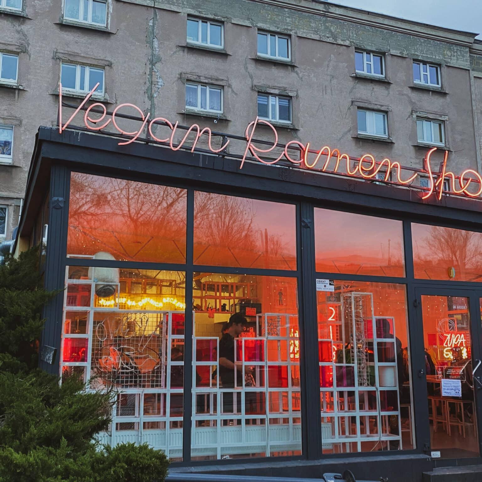 The Vegan Ramen Shop stands out with its open ambiance and colorful, bright interior against a gray building backdrop.
