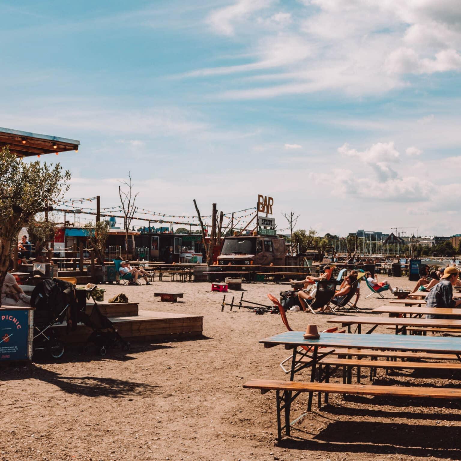 En el acogedor exterior del Mercado de comida callejera Reffen en Copenhague, los huéspedes pueden disfrutar de su comida en sillas de playa en la arena o en mesas de cerveza.