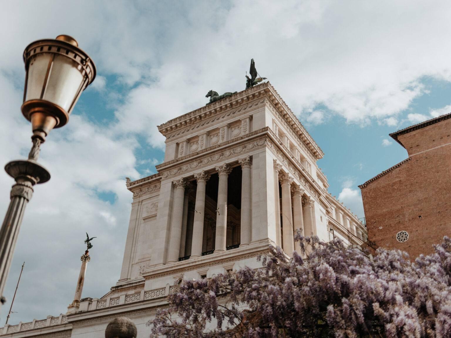 Vittorio Emanuele II Monument in Rome with columns, equestrian statue, and blooming wisteria.