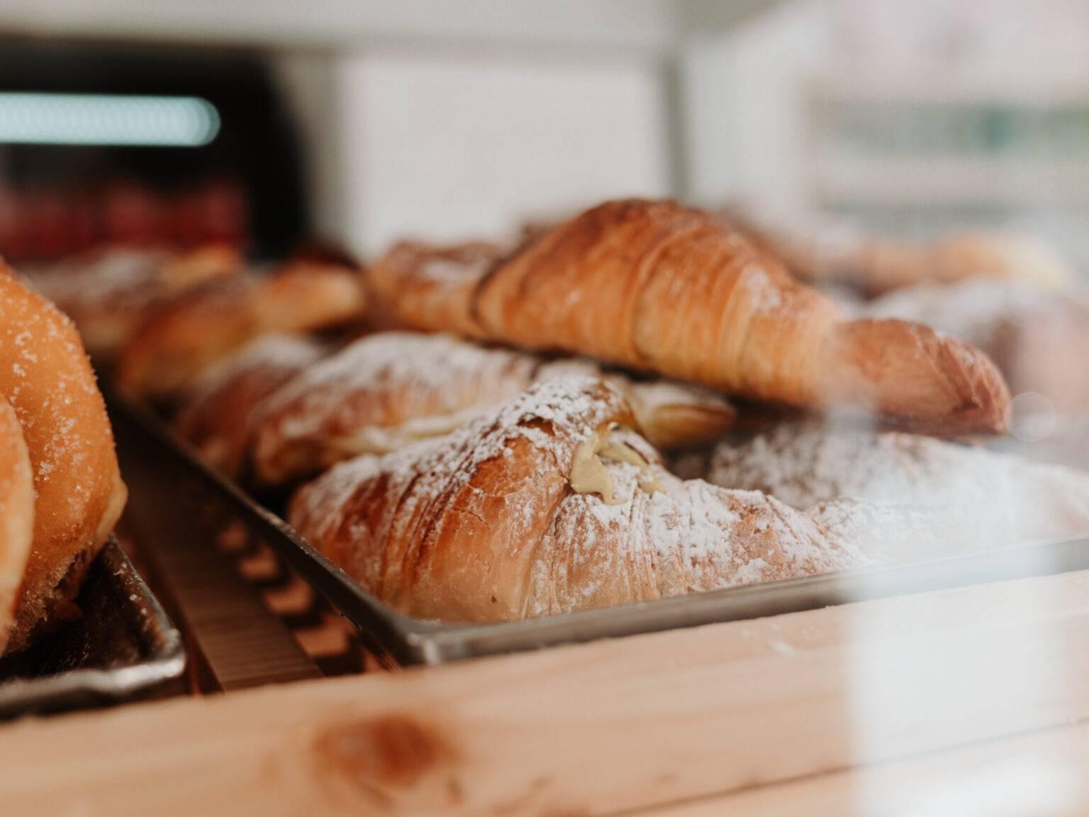Freshly baked cornetti dusted with powdered sugar in an Italian bakery.