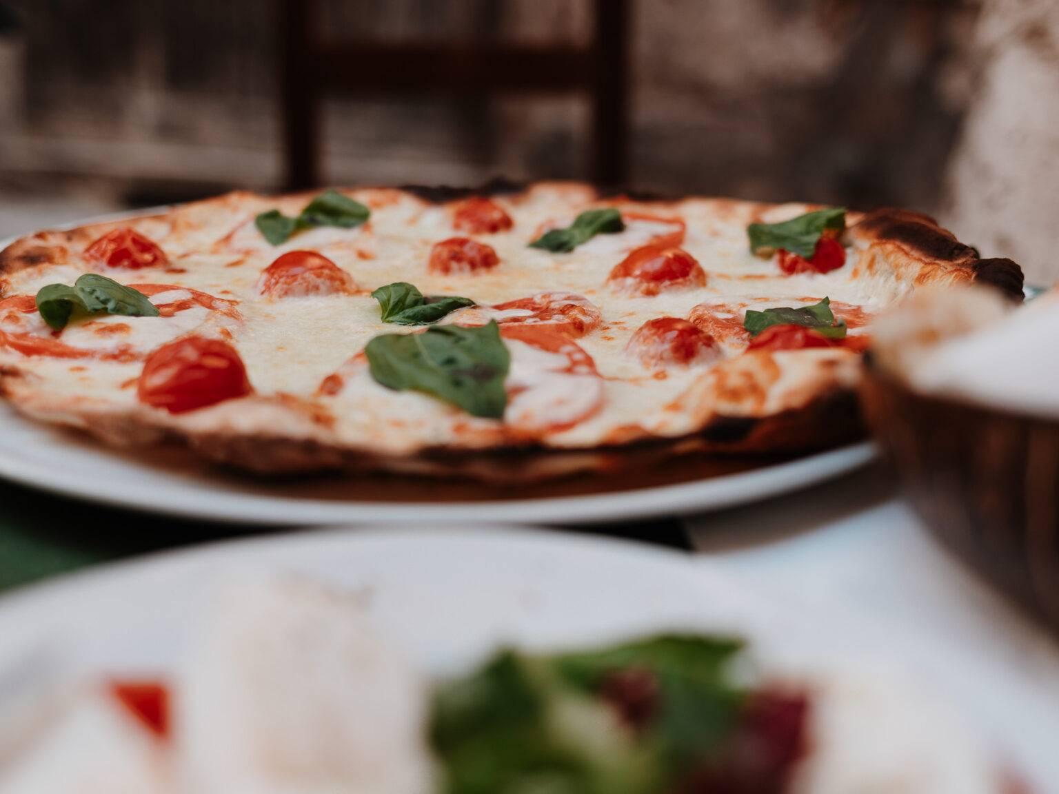 Crispy Margherita pizza with tomatoes and basil served at Lo Zozzone in Rome.
