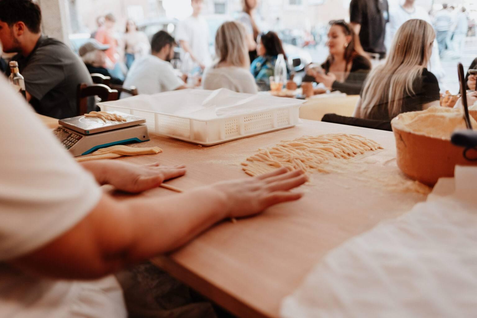 Fresh pasta is handmade at Osteria da Fortunata in Rome, with guests sitting in the background.
