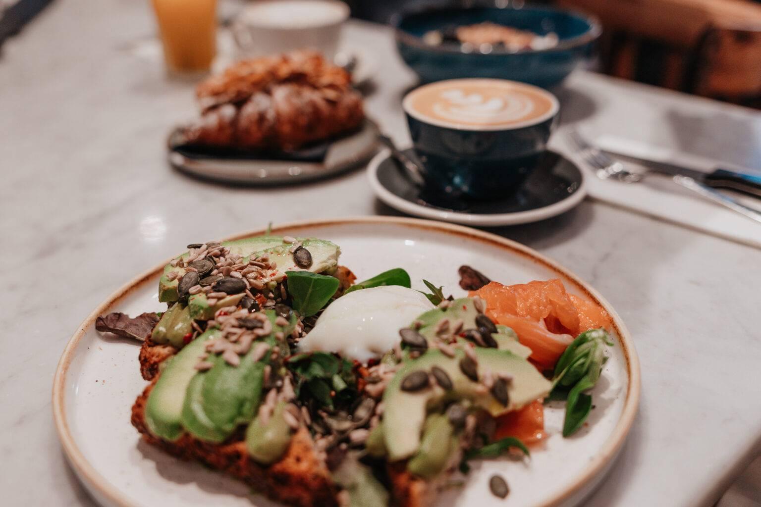Breakfast plate at Barnum in Rome with avocado toast, poached egg, salmon, and coffee.
