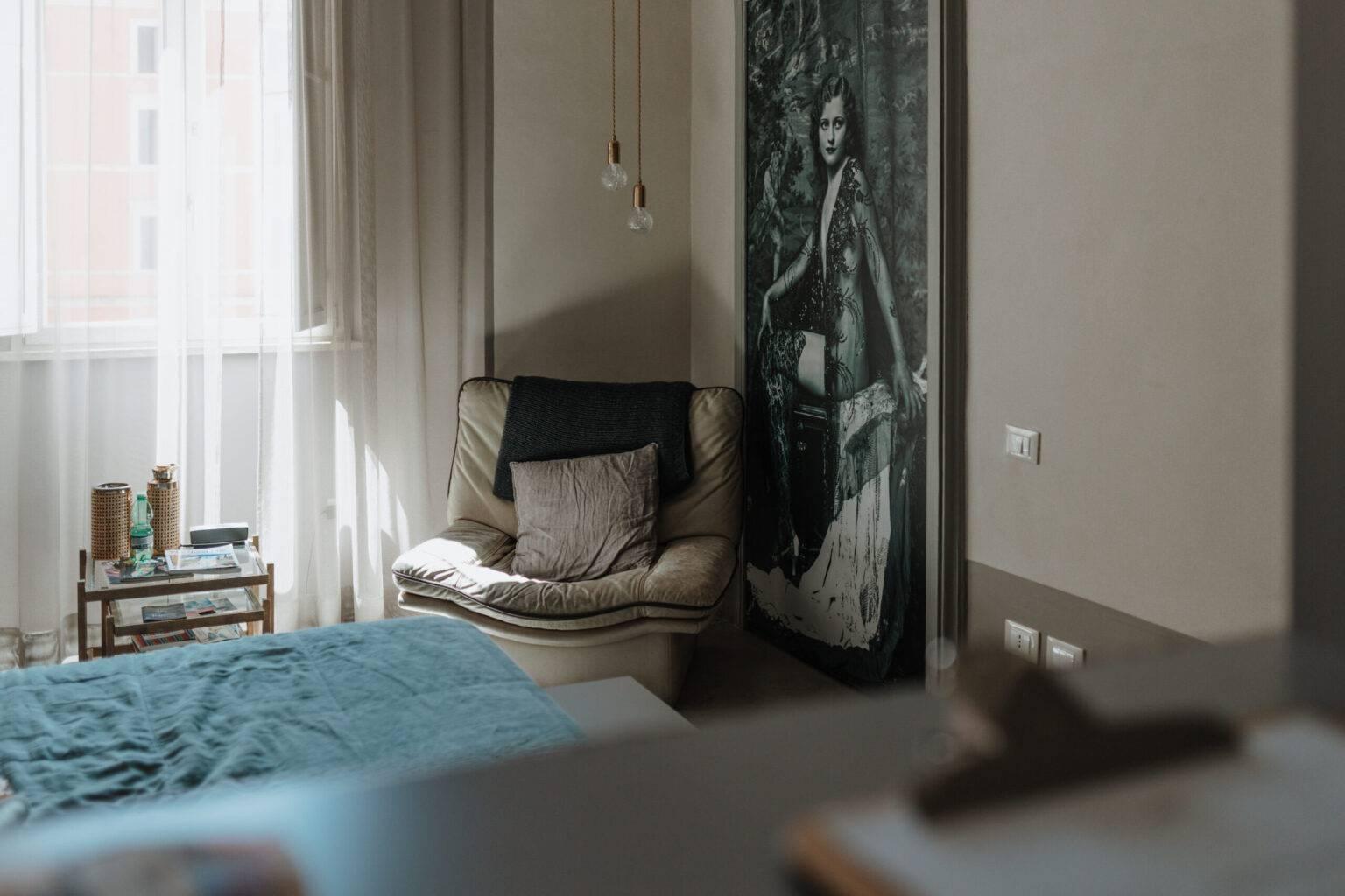 Cozy room at CasaCau near Trevi Fountain with armchair, art photo, and play of light.