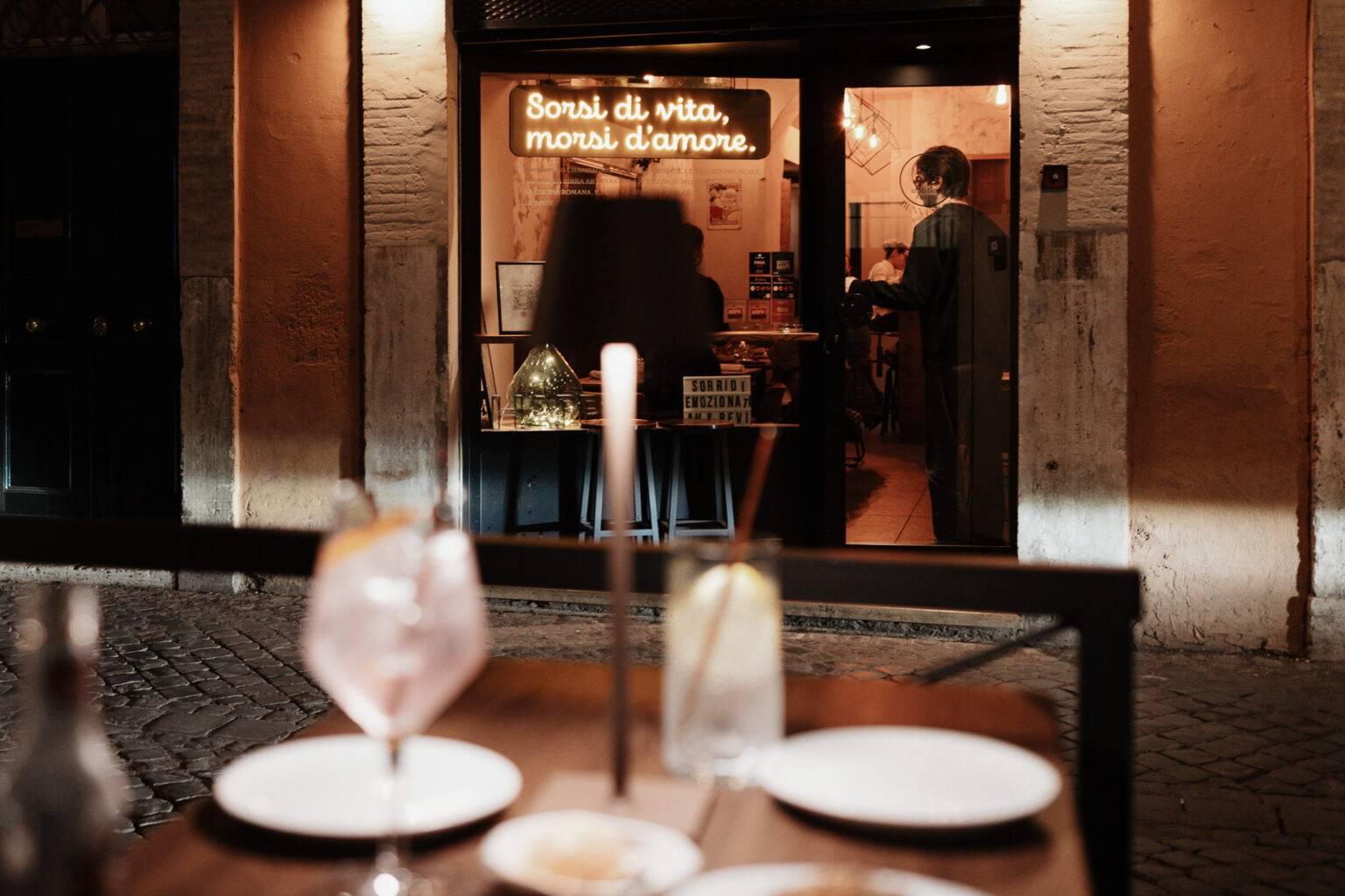 Evening ambiance in front of the restaurant 53 Untitled in Rome with a set table and illuminated entrance.