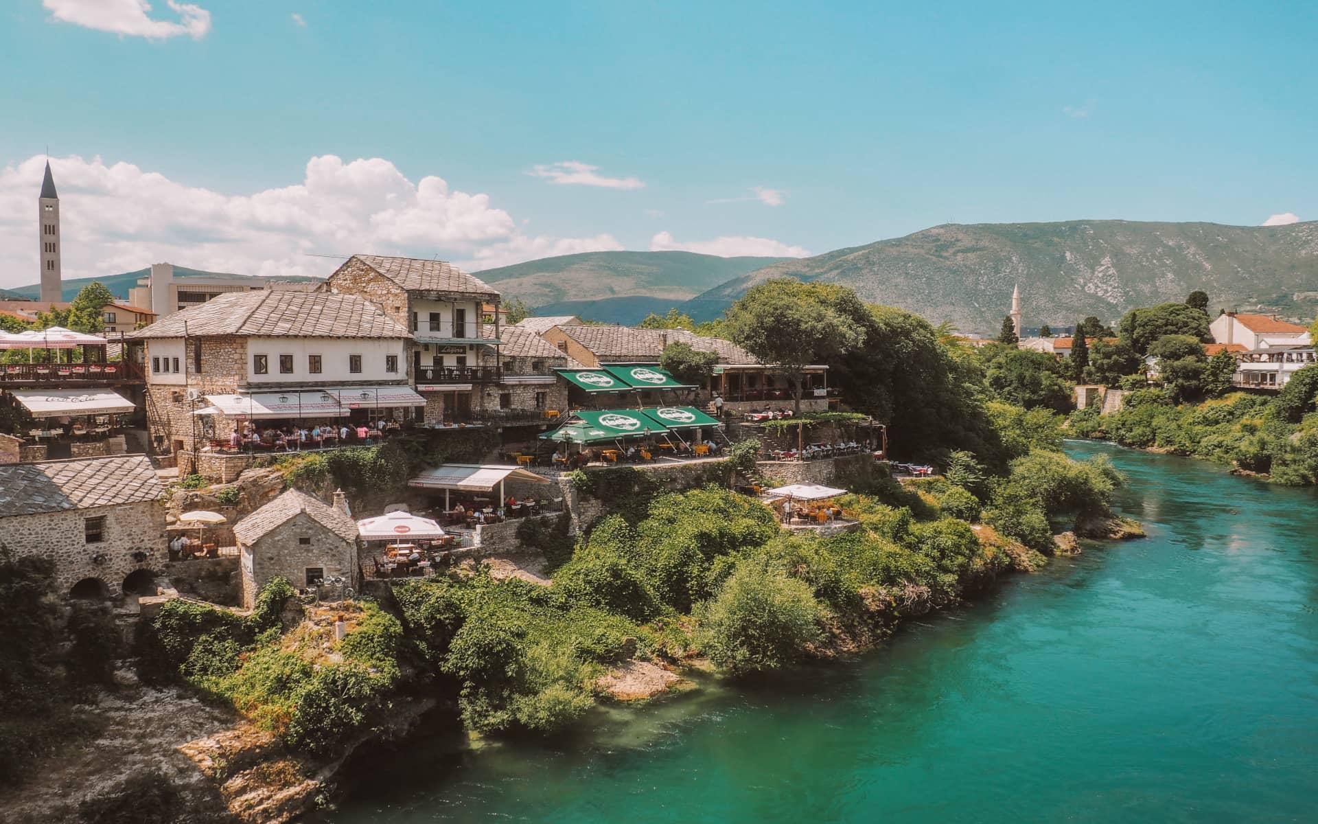Un río turquesa serpentea a lo largo de un pueblo en Bosnia y Herzegovina.