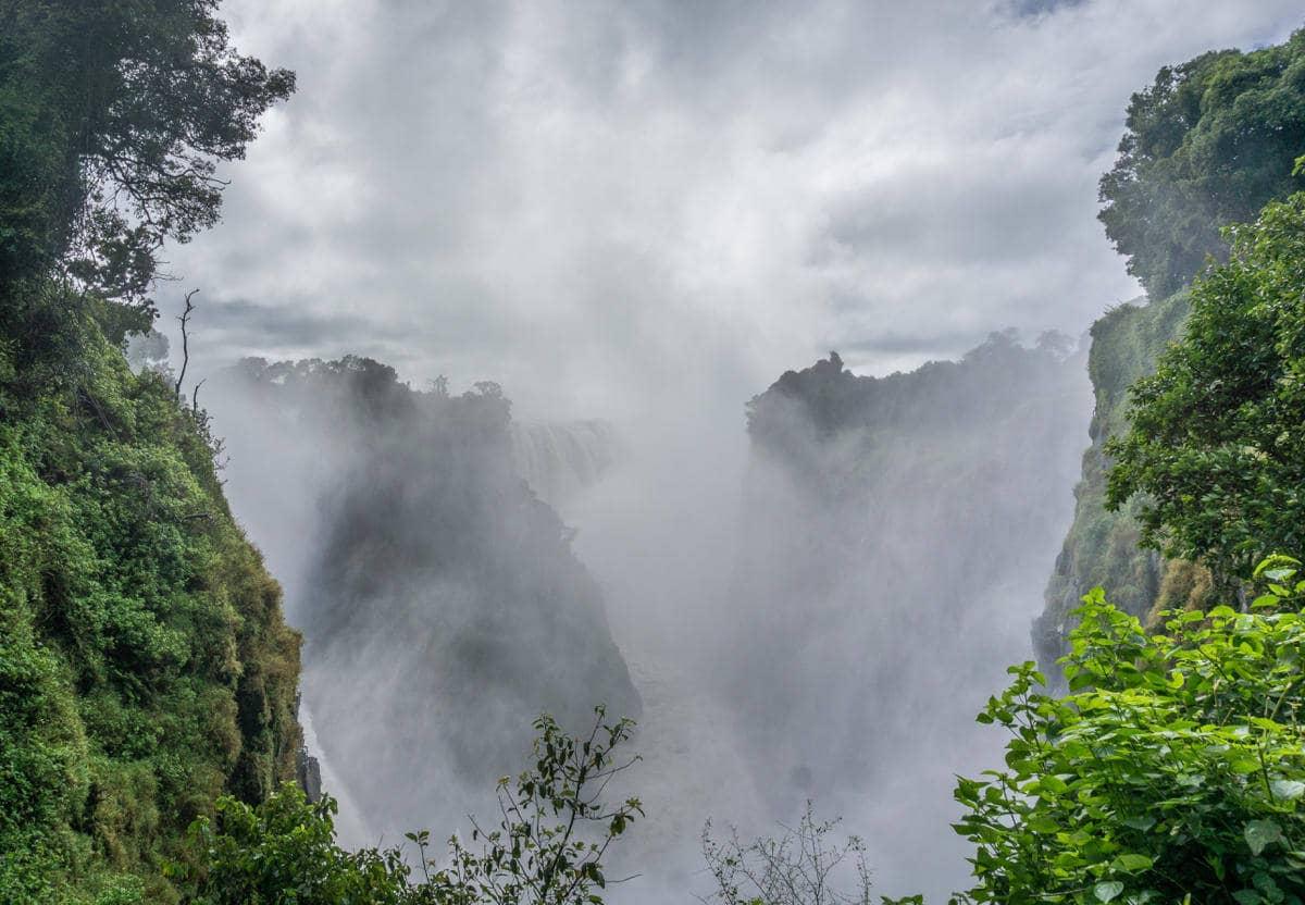 En las Cataratas Victoria, la niebla del agua sube entre la vegetación exuberante.