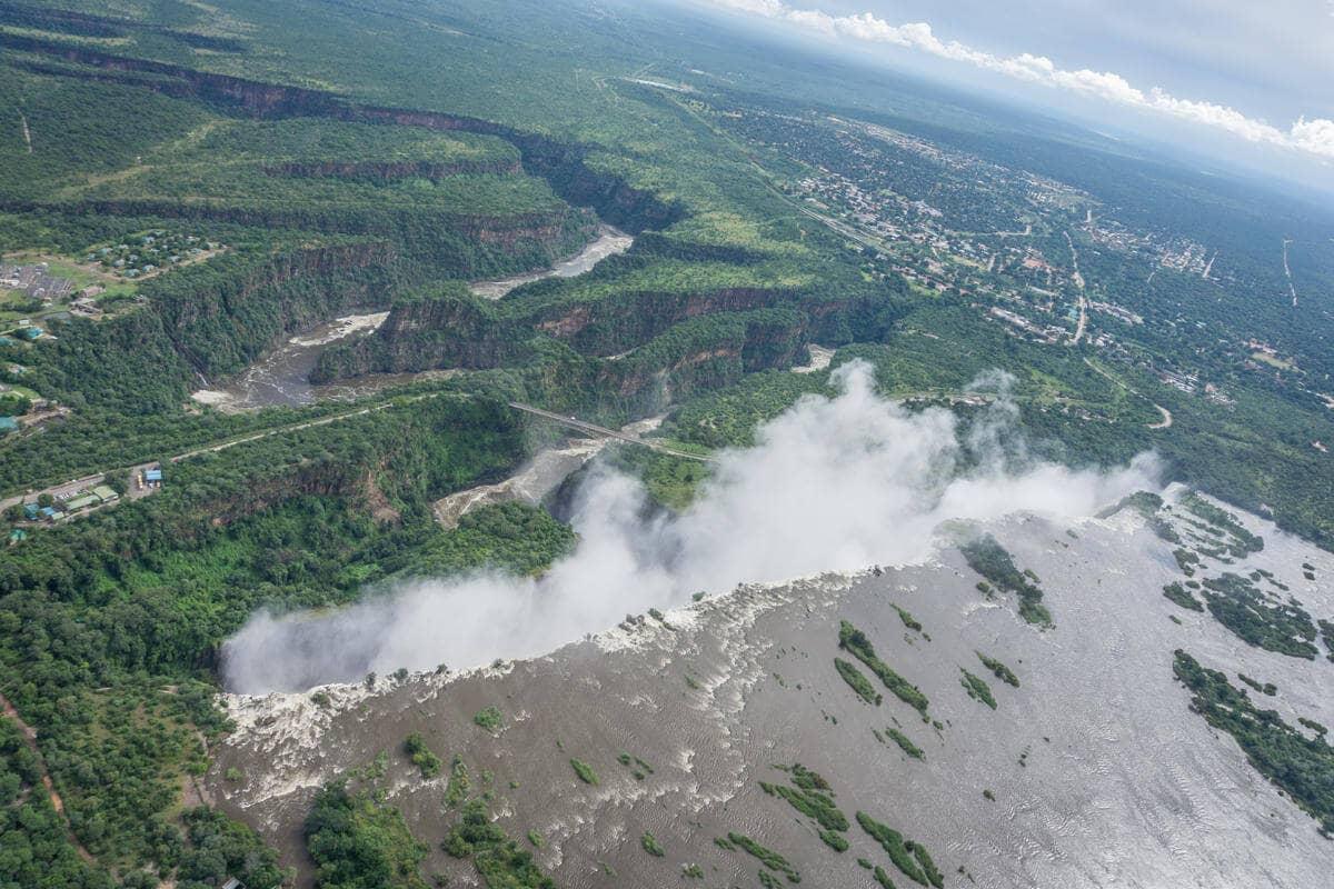 Vista de la vasta extensión de las Cataratas Victoria y su niebla que asciende al cielo desde un helicóptero.