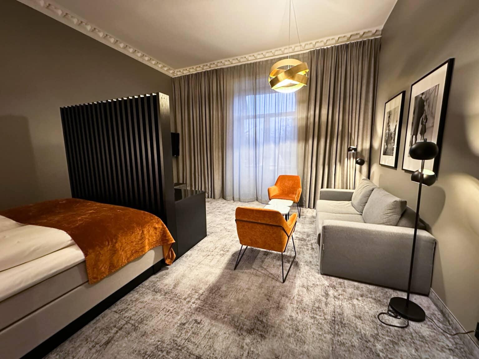 A room at the Karl Johan Hotel in Oslo with gray and orange furniture.