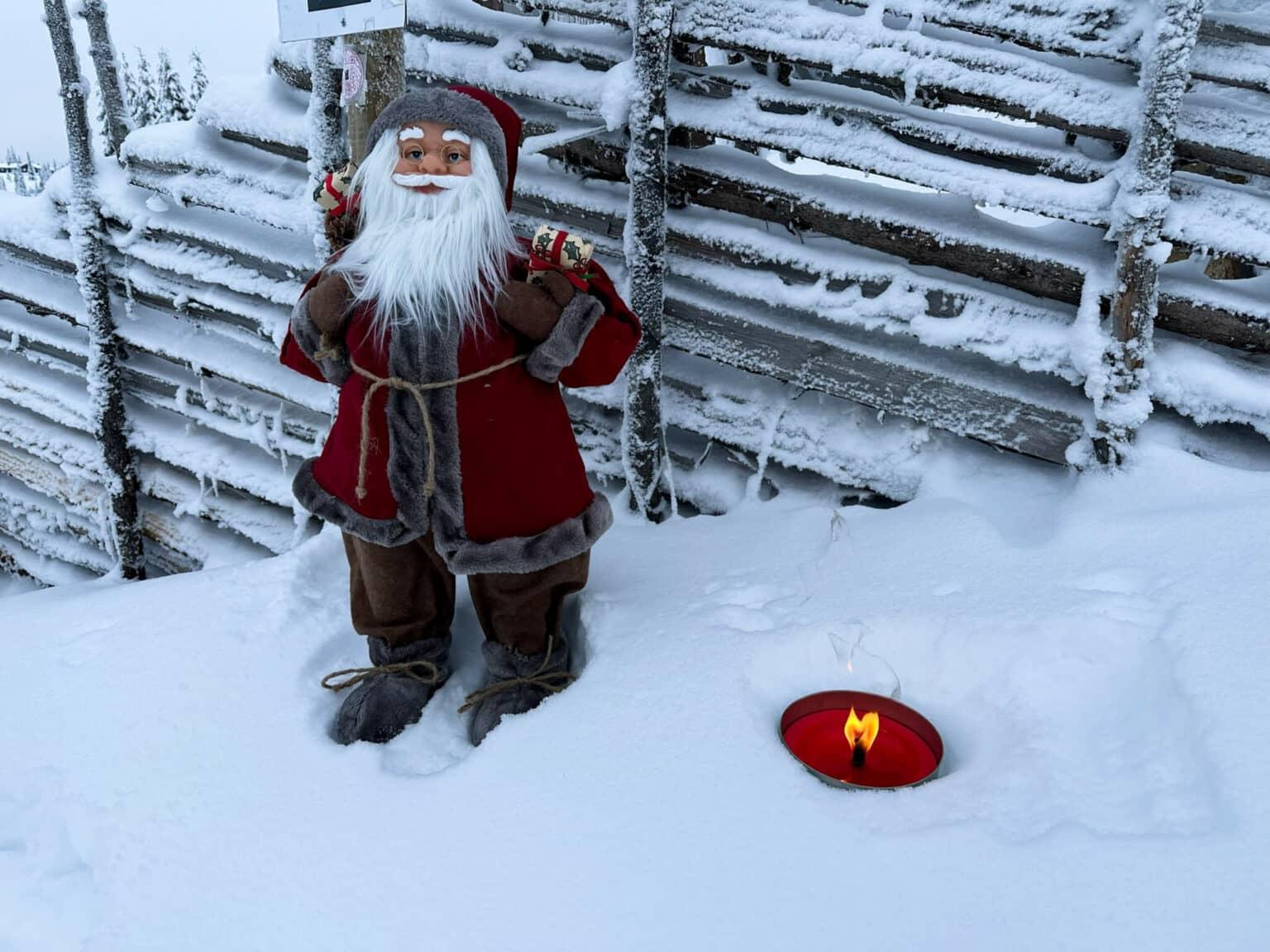 A small Santa figure in a red coat in the snow.