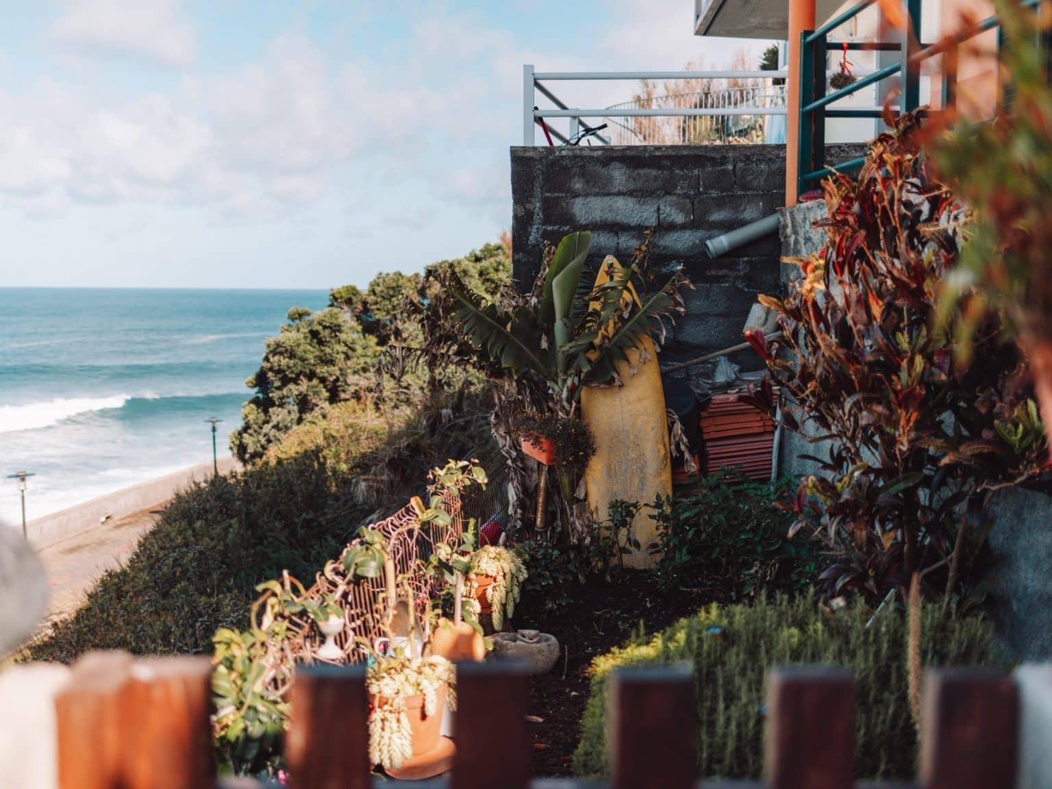 A small courtyard behind a house with stairs leading down to the beach