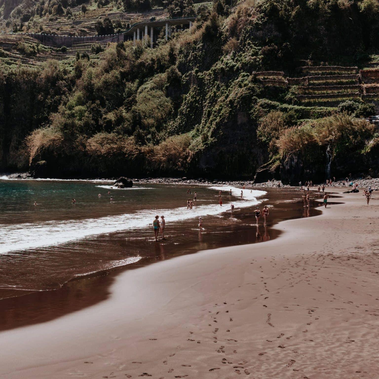 A flat beach in a green bay: left turquoise water, right dark sand.