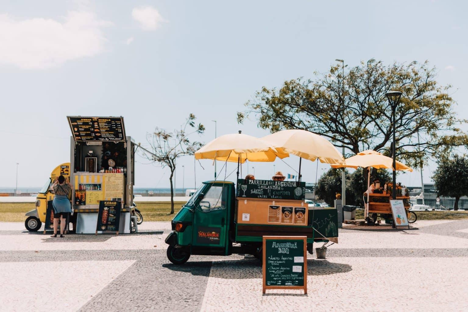Small market tricycles offer various products, with the Atlantic coast in the background.