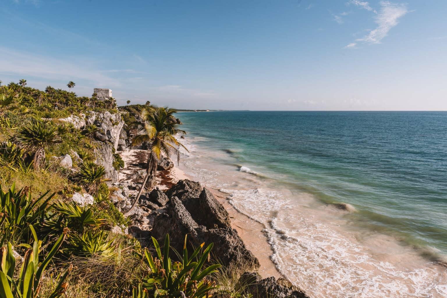 A green-clad rocky coast at the ruins in Tulum, Yucatán, enchants with blue shining sea.