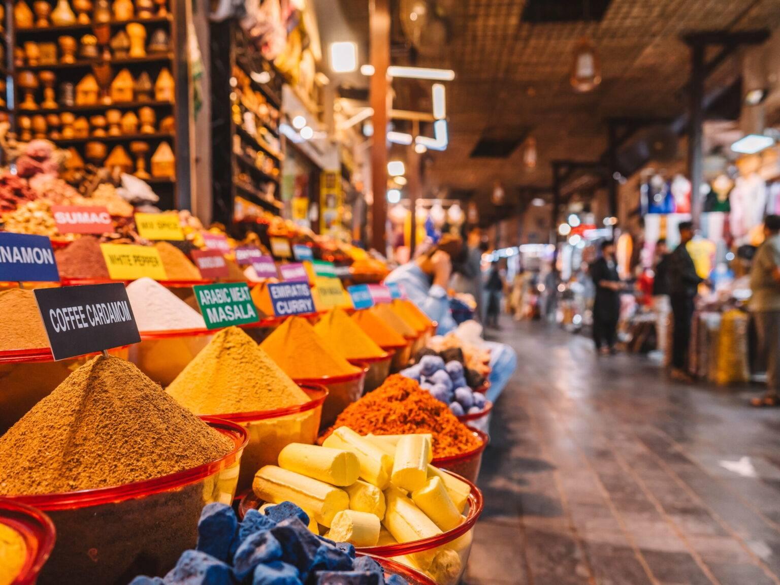Un puesto de especias con varios cuencos llenos de diferentes especias de colores en una calle comercial.