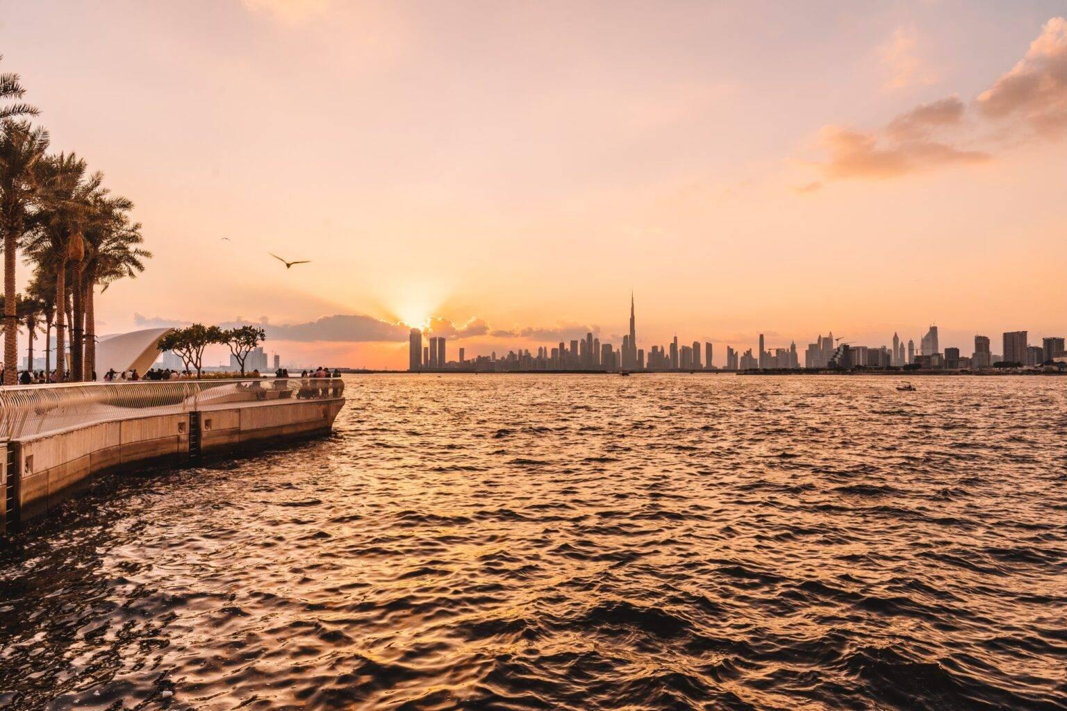 El Creek Habour en Dubái con la línea de horizonte de la ciudad de fondo al atardecer.