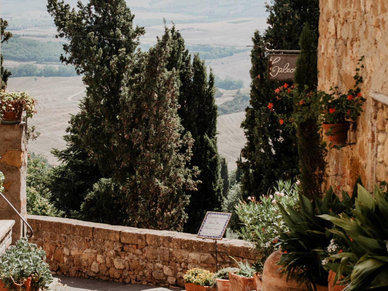 Una terraza con macetas de flores y vista a las colinas de la Toscana.