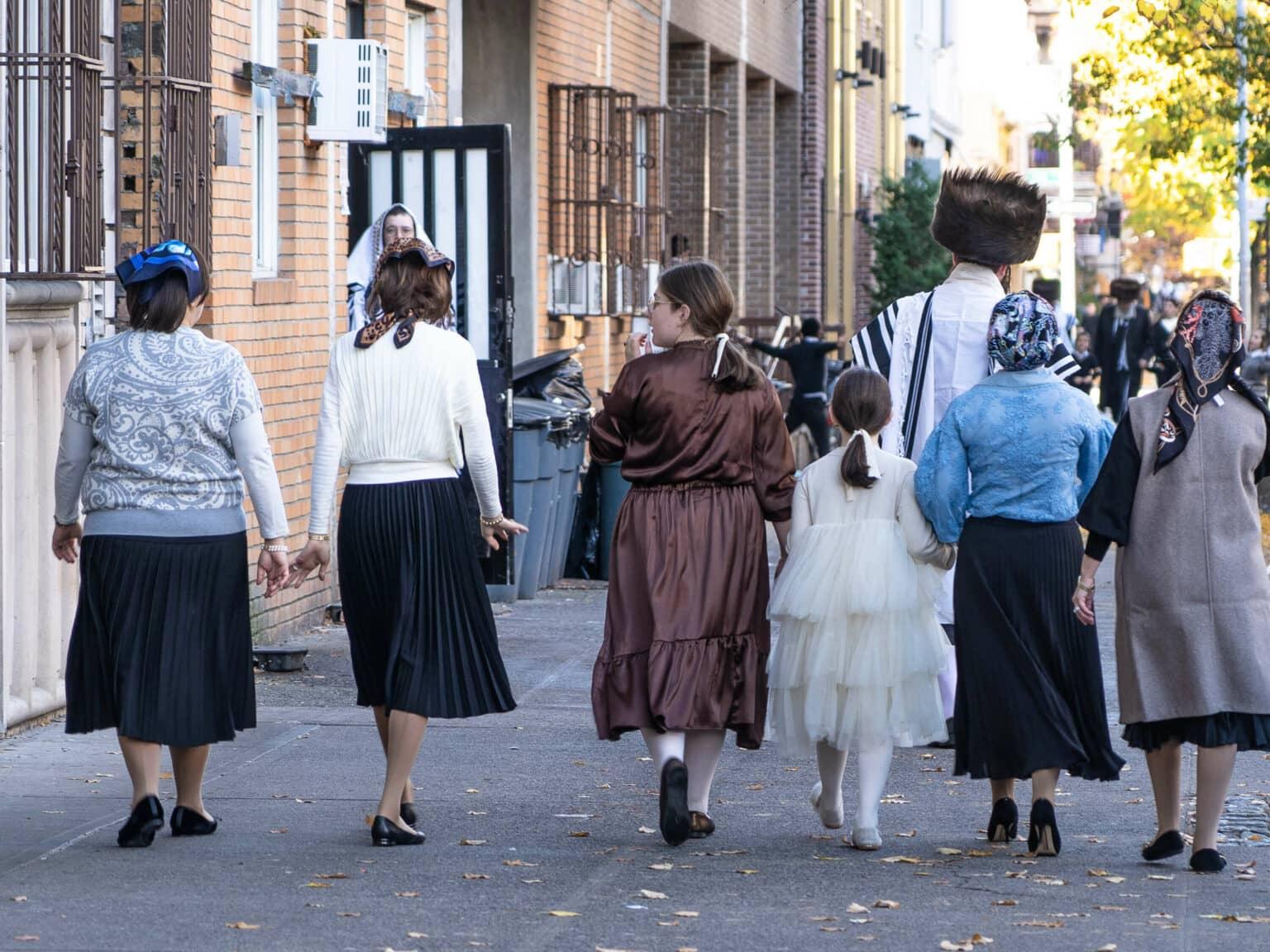 A group of Hasidic Jewish women wearing traditional clothing and headscarves walking down a street in the Williamsburg neighborhood of Brooklyn.