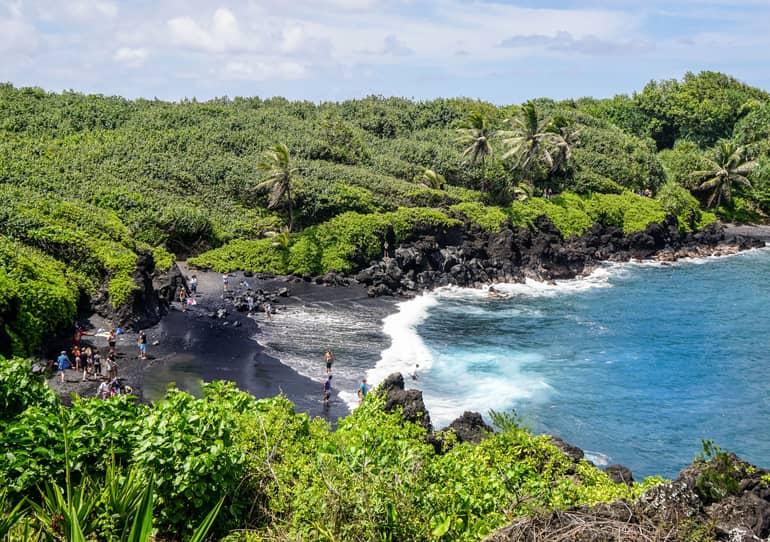 La playa Waianapanapa en Maui, Hawái, es famosa por su arena de color negro, un paisaje verde lo rodea.