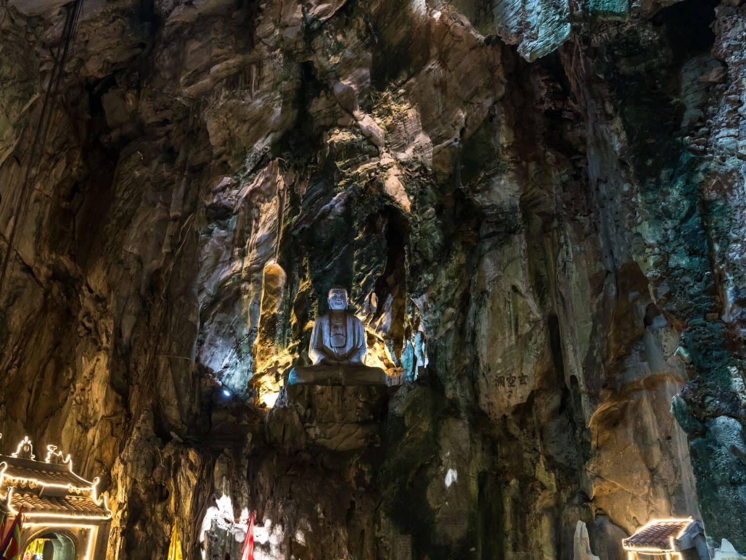 Biggi in a cave with a Buddha statue in the Marble Mountains.