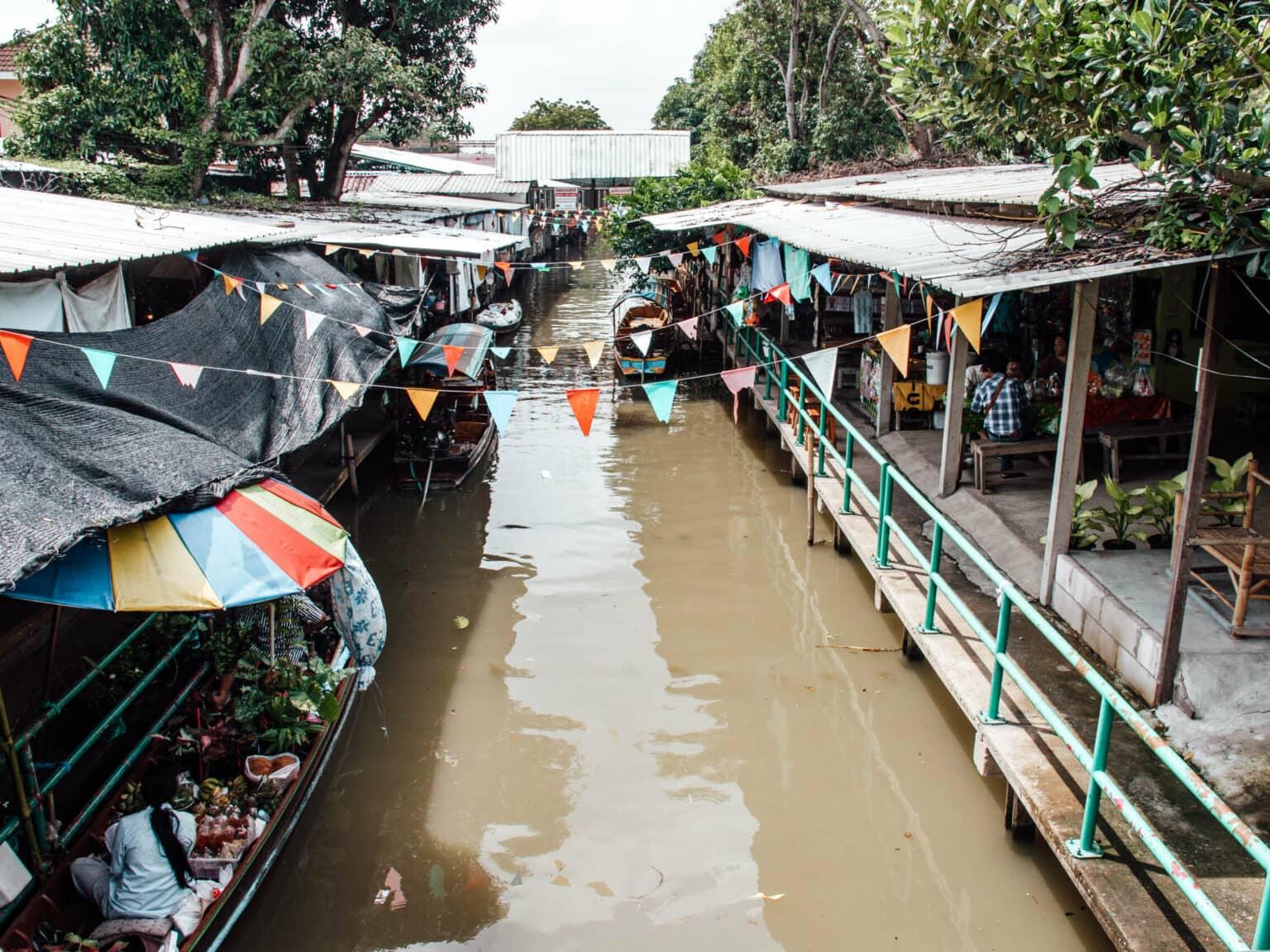 Houses line the banks of the Lat Ta Niao Canal with small boats floating nearby.