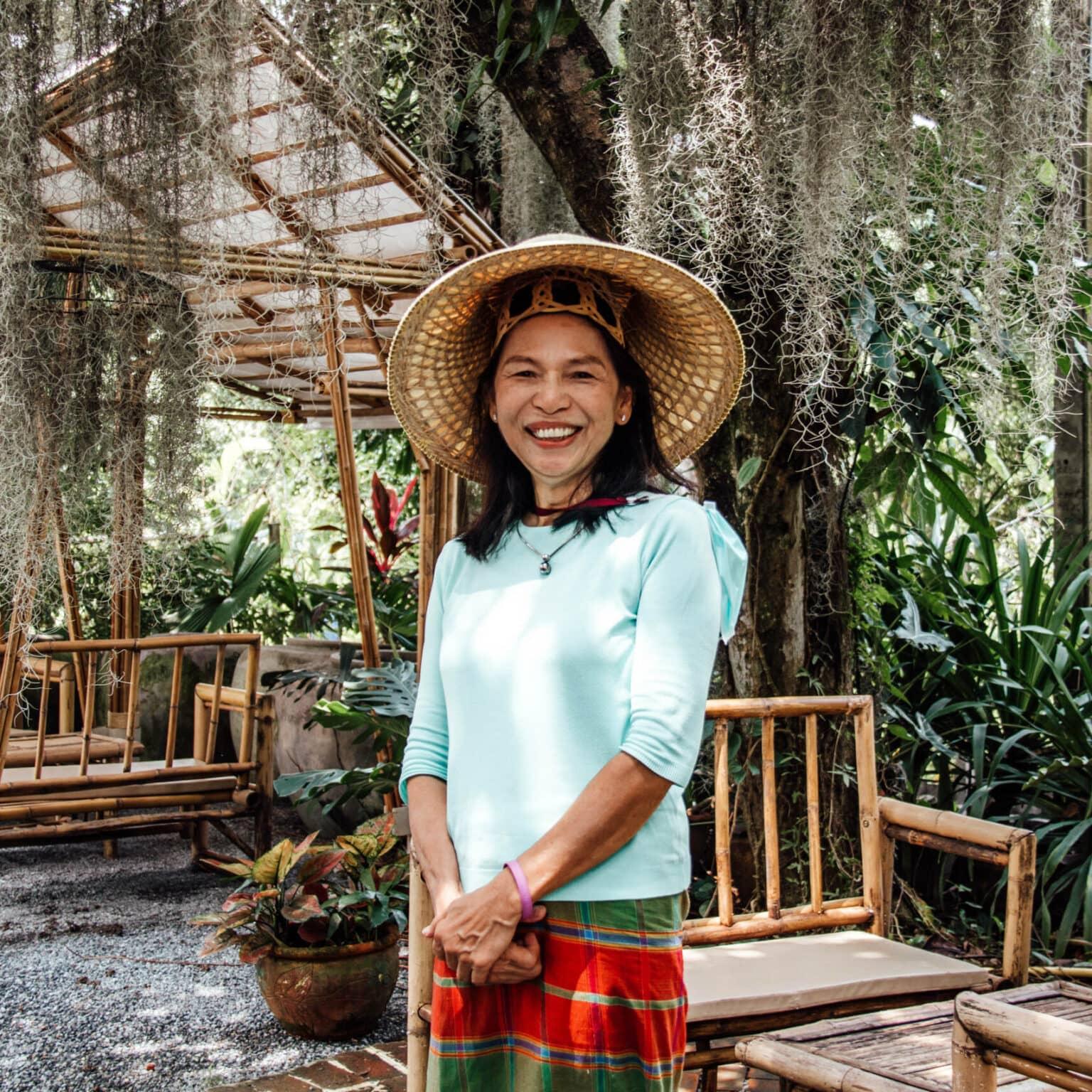 A woman stands in the foreground of the Natura Café, surrounded by plants.