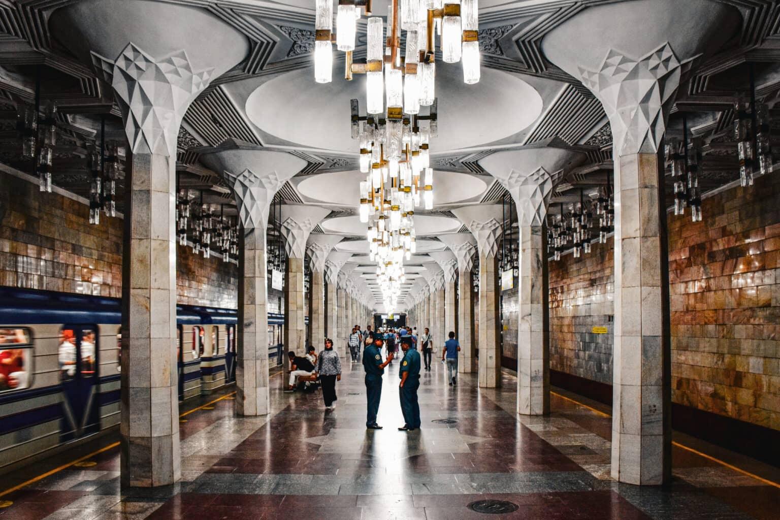 Interior view of the Mustaqillik Maydoni Metro Station in Tashkent with tall columns and decorative lights