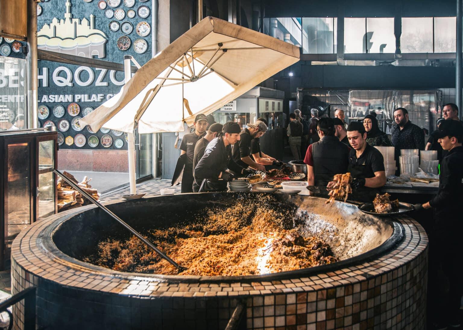 Chefs preparing traditional plov in a huge cauldron at the Besh-Qozon restaurant in Tashkent