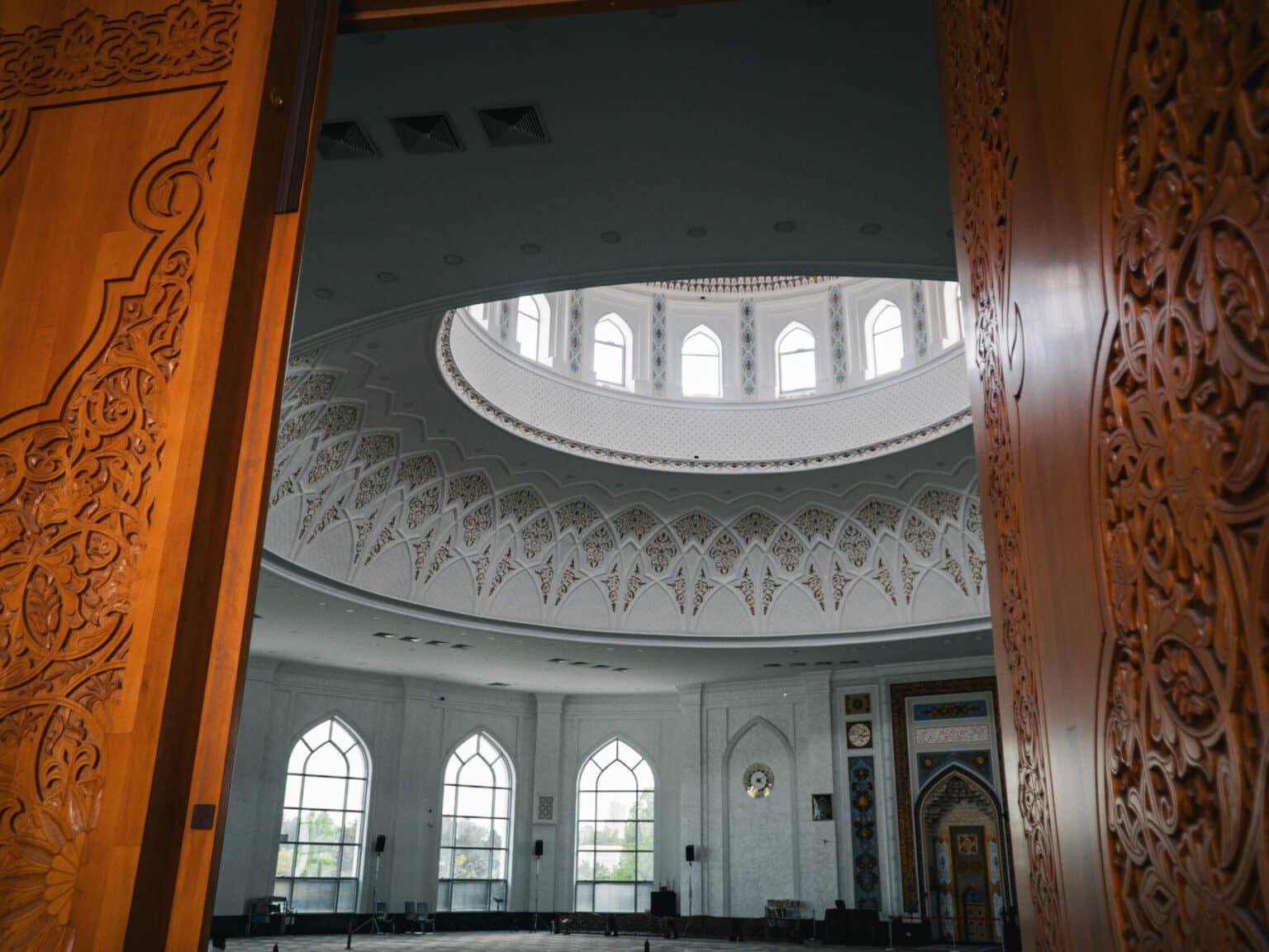 Interior view of the Minor Mosque in Tashkent with decorated walls, large dome, and carved wooden doors