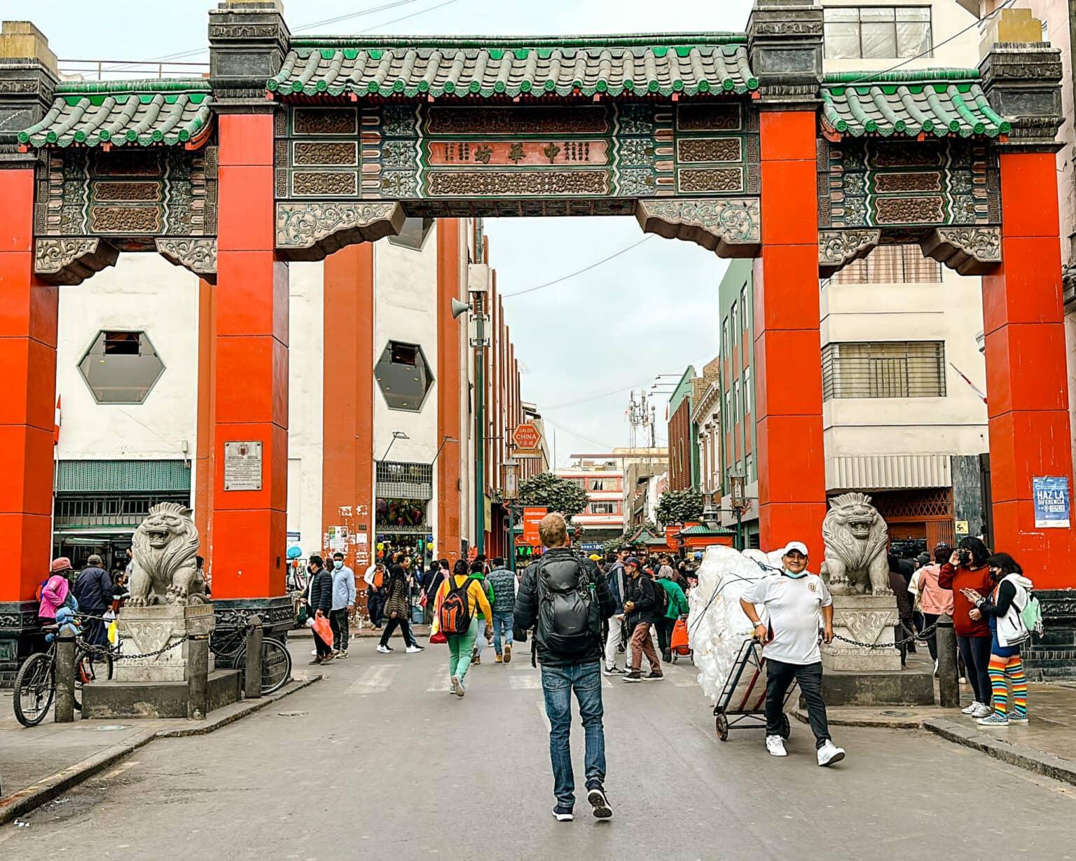 A gate with red columns and a green roof that opens the way to Chinatown in Lima.