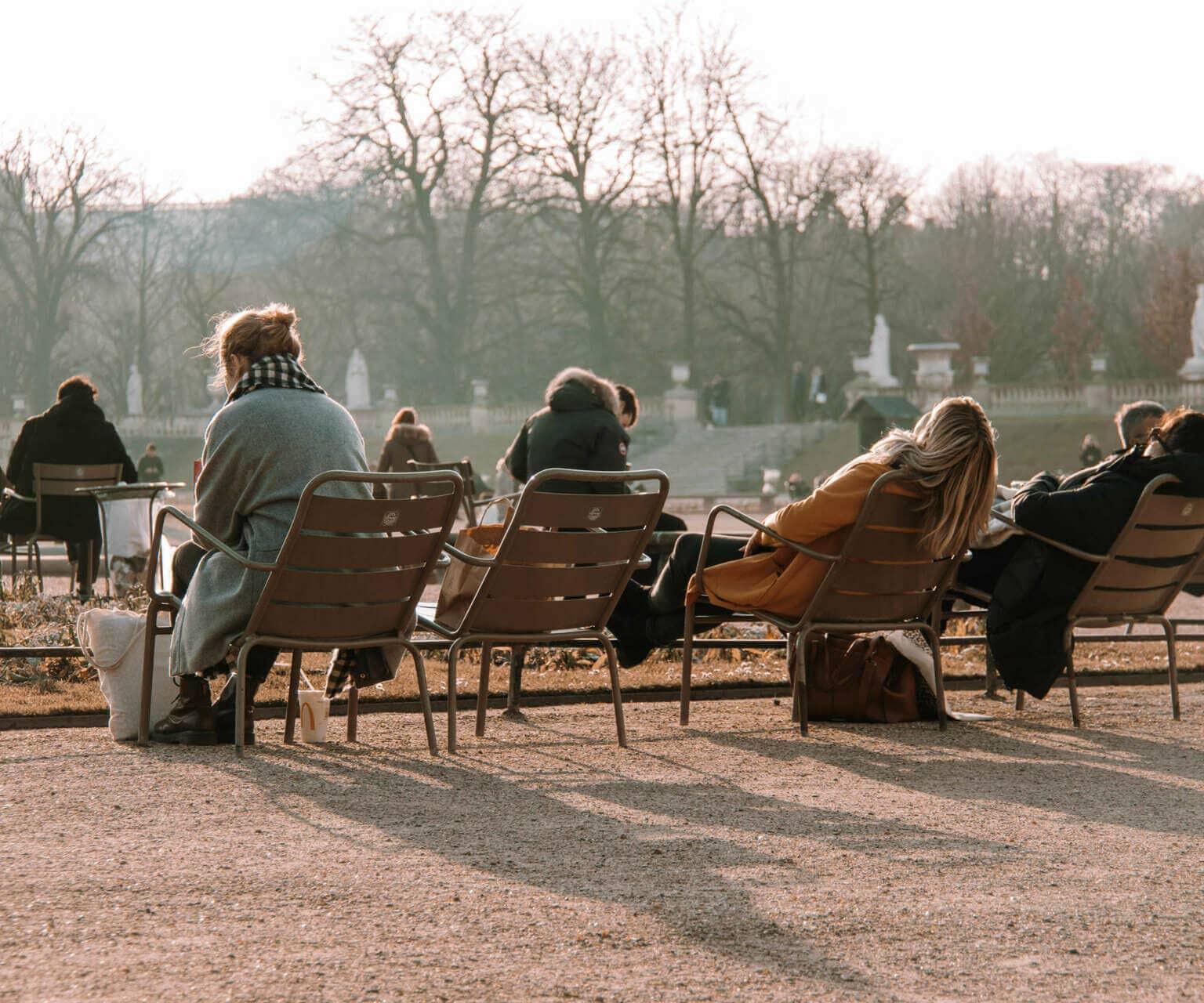 En el Jardin du Luxembourg en París, tanto los locales como los viajeros disfrutan de los rayos del sol en las sillas dispuestas para los visitantes.