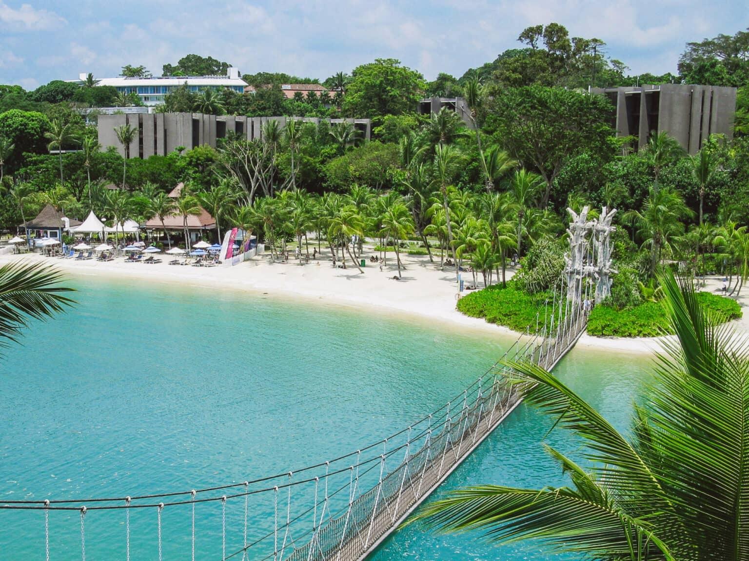 Mar azul turquesa con una playa de arena adornada con palmeras en la oasis Sentosa de Singapur.