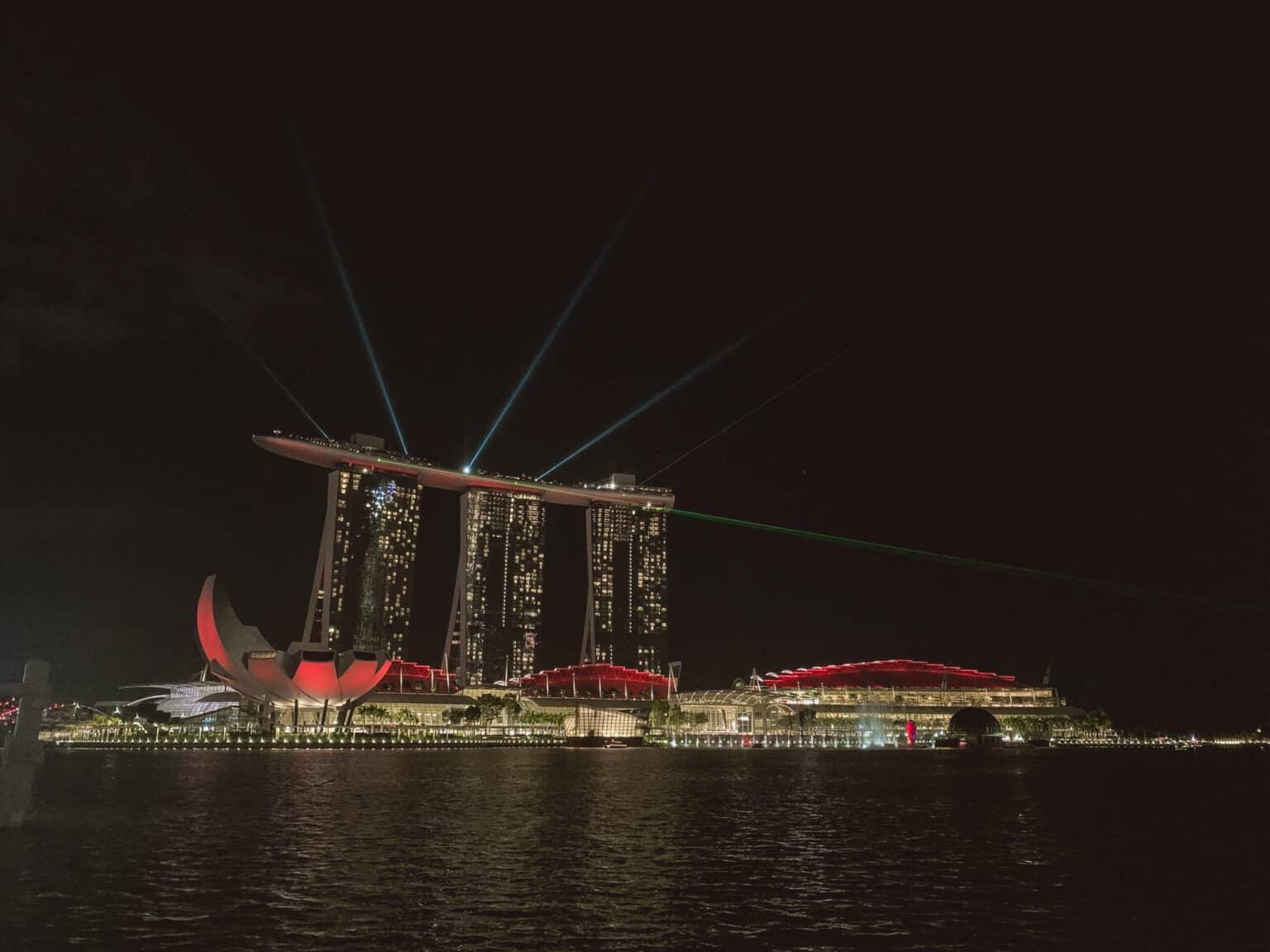 Las luces de colores del espectáculo "Spectra" brillan en el oscuro cielo nocturno de Singapur y se reflejan en el agua.