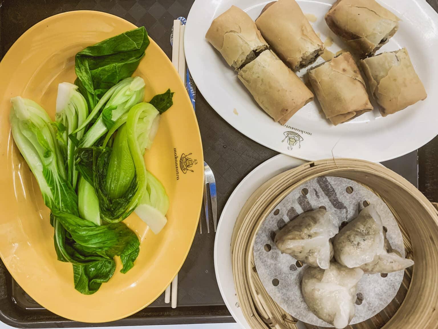 Tres platos con varias delicias del mercado Makansutra Gluttons Bay en Singapur.