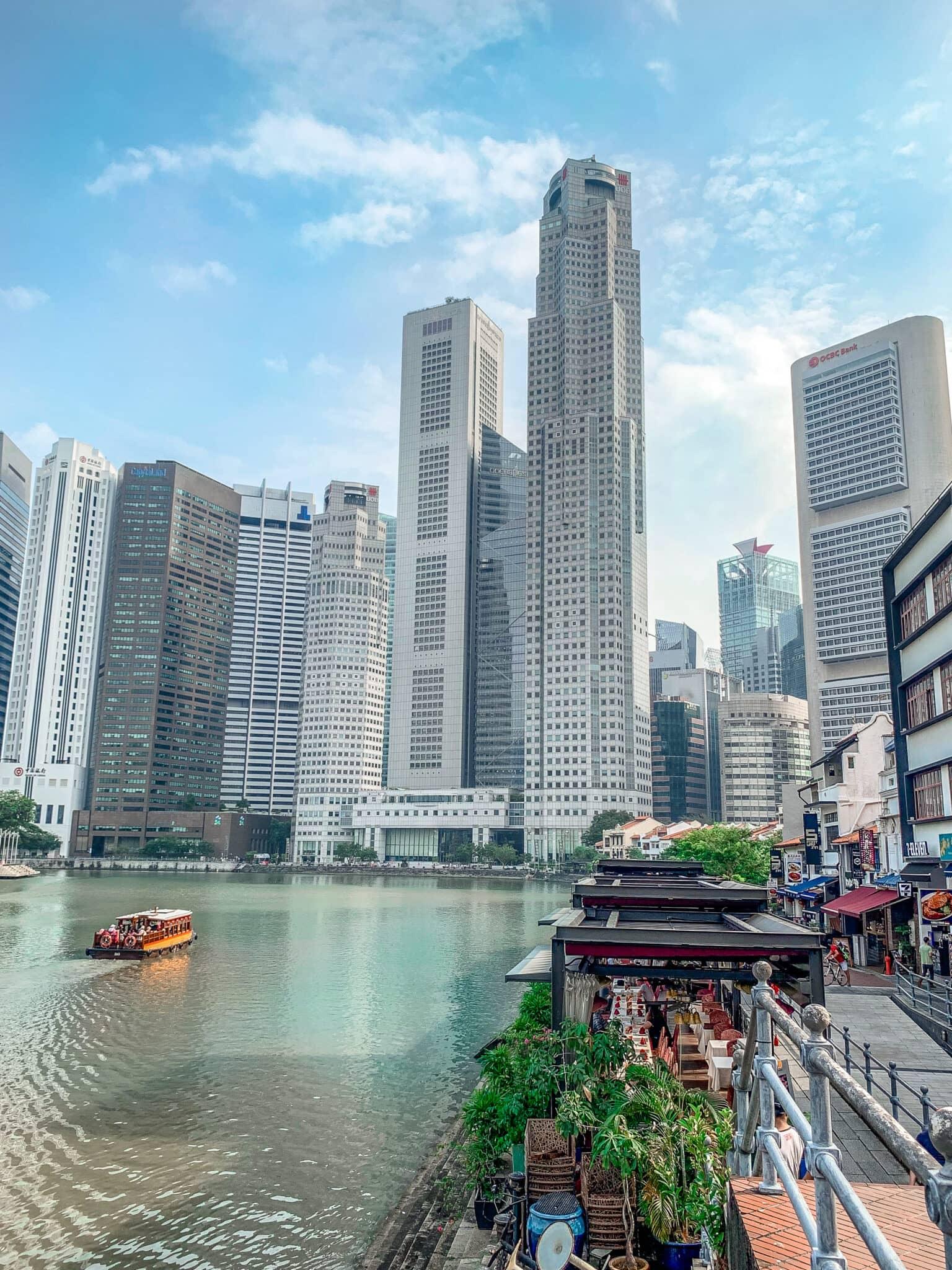 Boat Quay en primer plano con vista al río Singapur y muchos rascacielos.