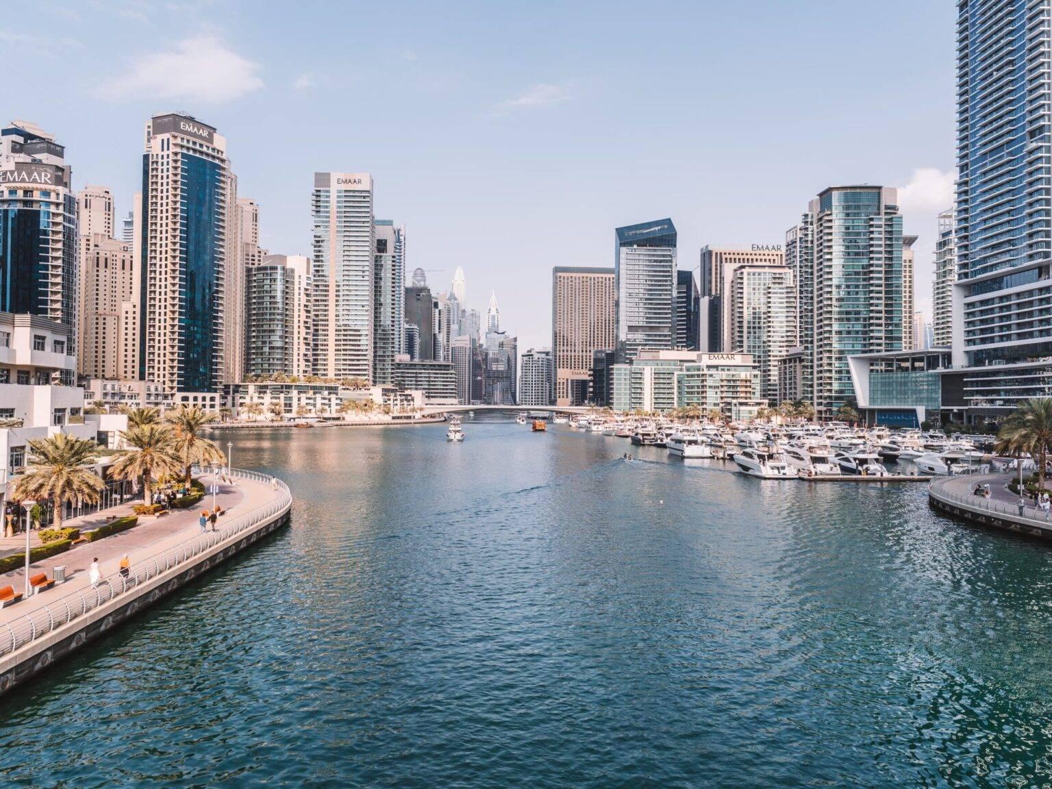 Dubai Marina with small yachts surrounded by skyscrapers.