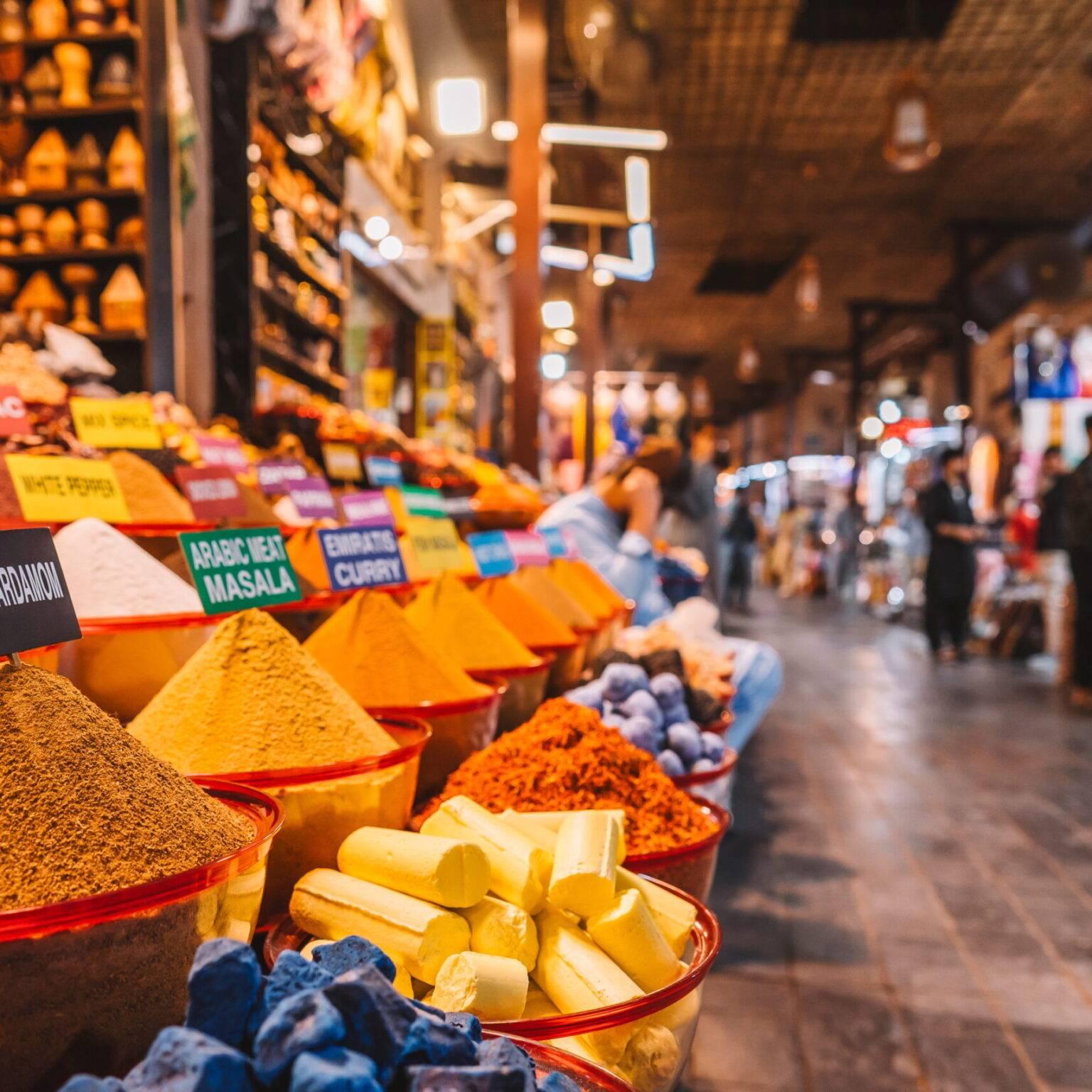 A spice stand with many bowls filled with colorful spice powders in a shopping street.