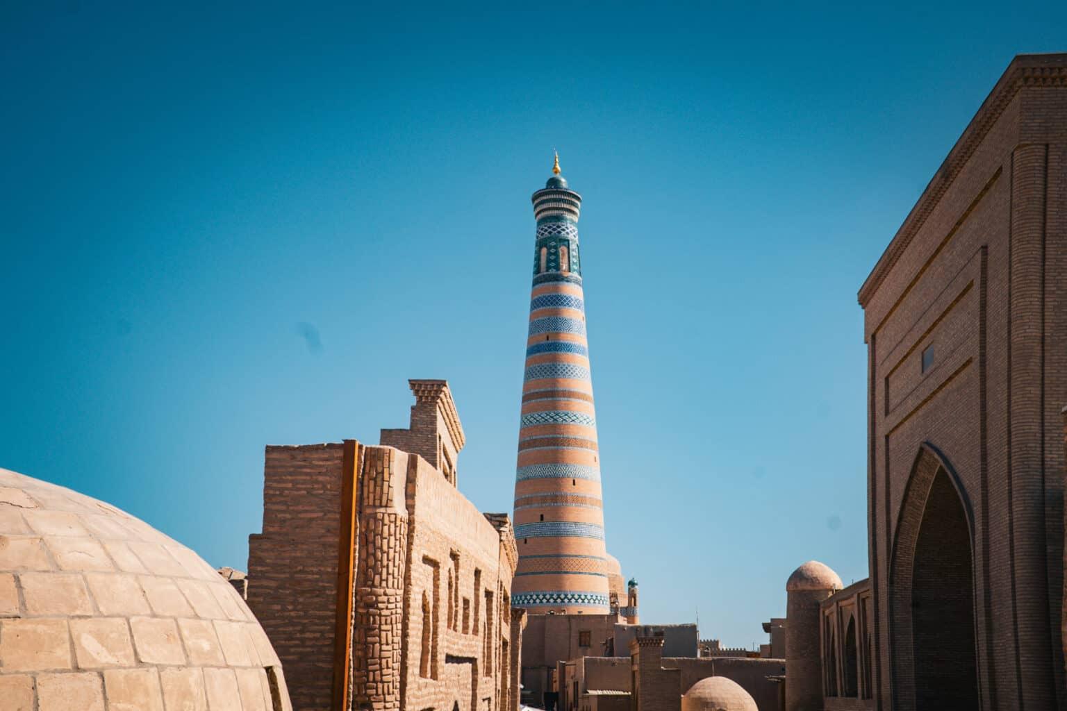 The Islam-Khodja Minaret in Khiva towers into the blue sky with its colorful patterns