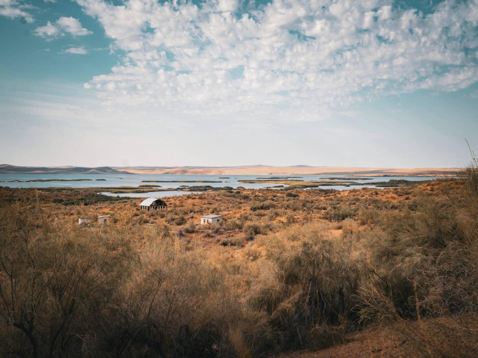 View of the Aydarkul Lake in Uzbekistan, surrounded by arid desert landscape and scattered cabins