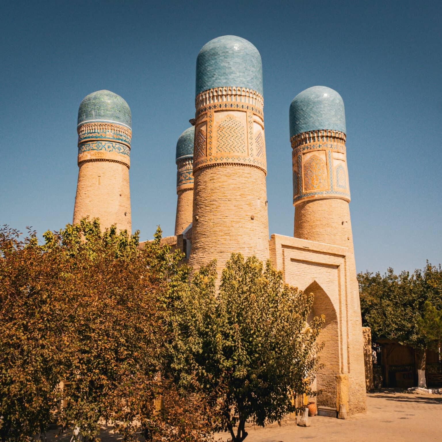 The four turquoise towers of the Chor-Minor in Bukhara, surrounded by trees