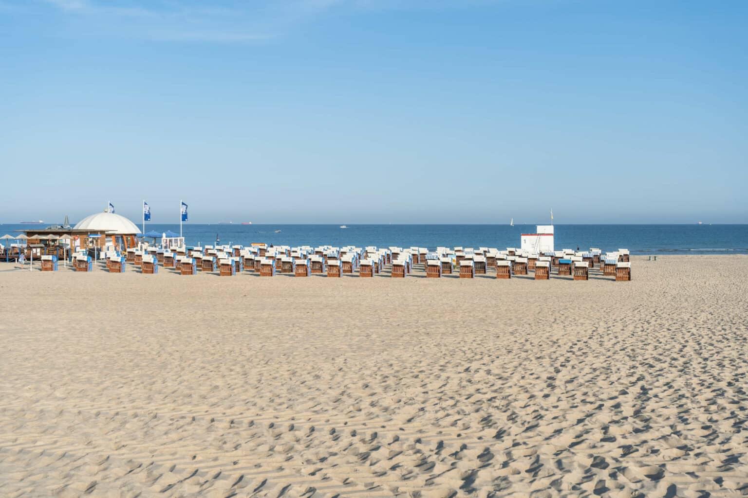 Sandy beach in Warnemünde with a view of the sea and beach chairs.