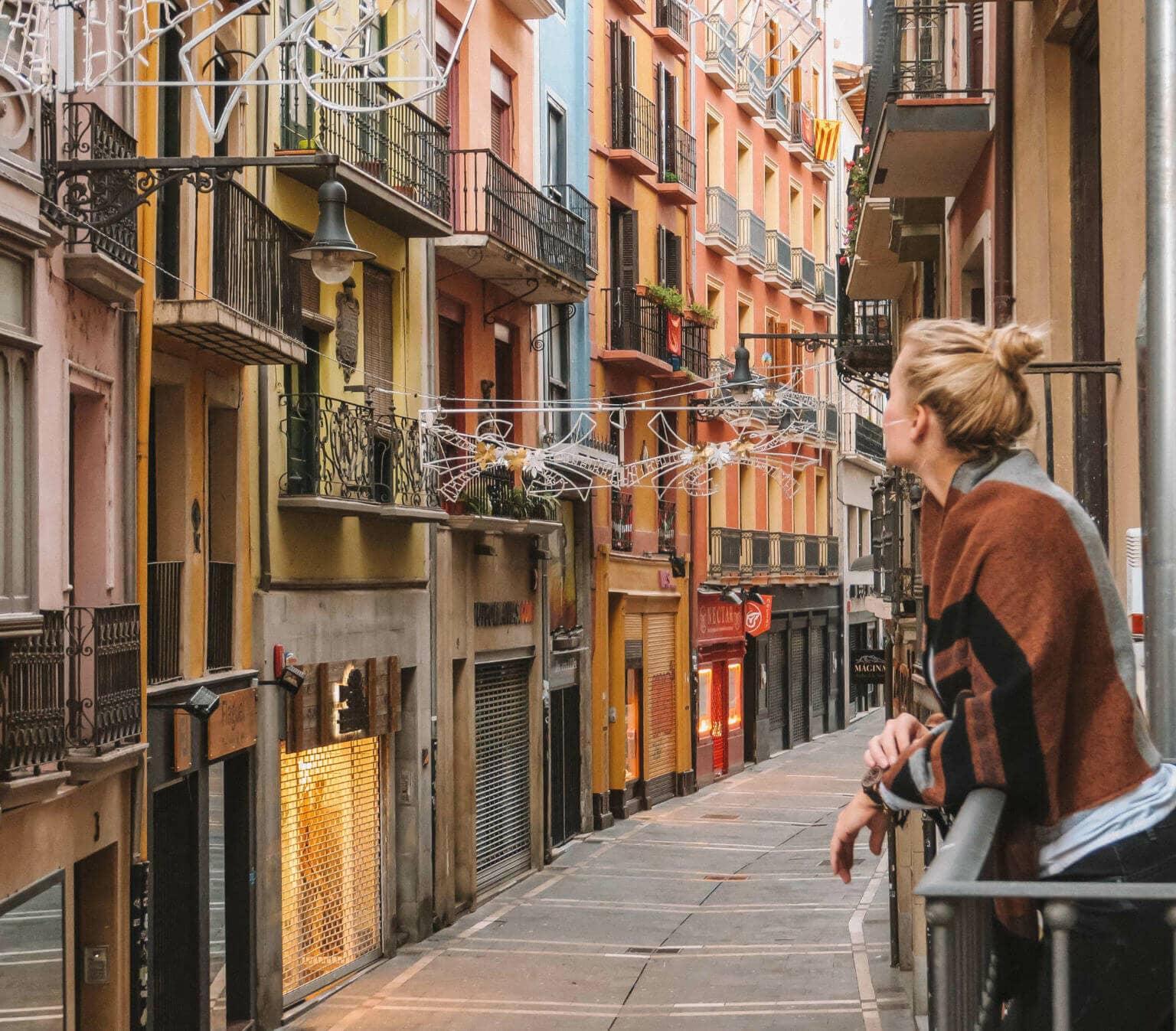 La bloguera de viajes Nina disfruta de la vista desde un pequeño balcón en una estrecha calle de la ciudad española de Pamplona.