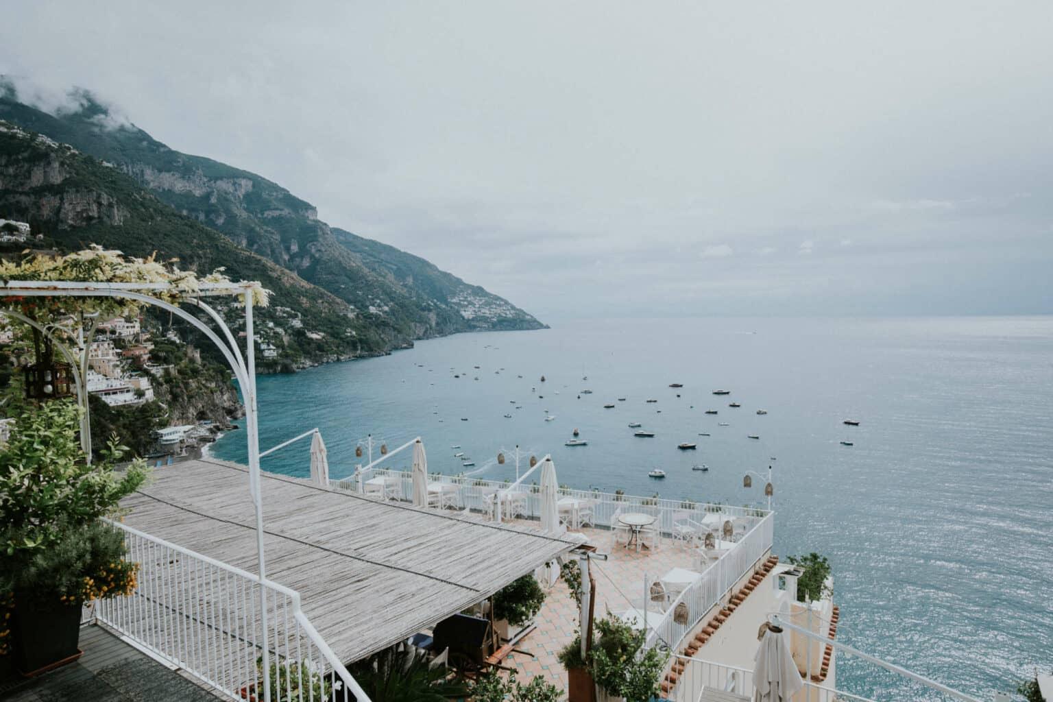From a balcony, you can see the sea where many boats are swimming.