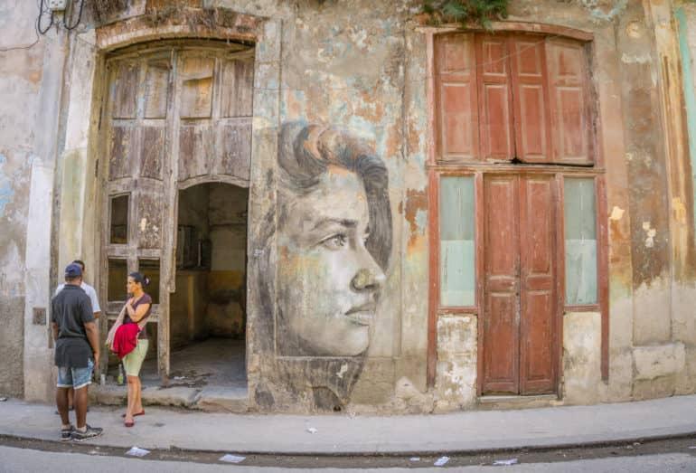 En una fachada de casas en una calle de La Habana se encuentra retratada una mujer atractiva.