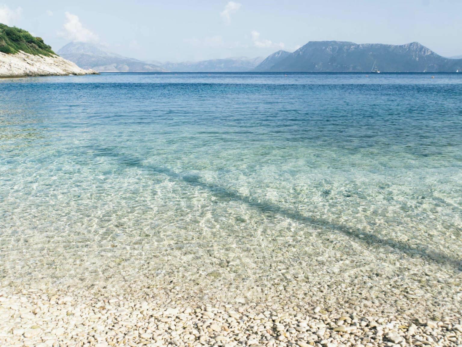 Crystal clear water at the pebble beach of Meganisi, the small neighboring island of Lefkada in the Ionian Sea.