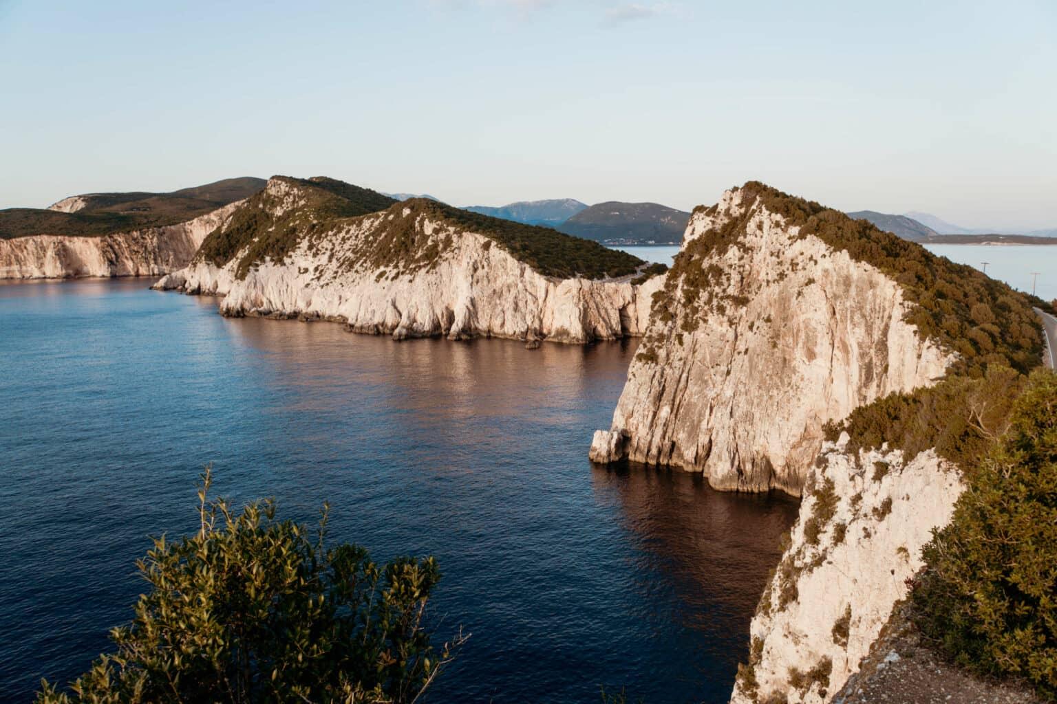 The sunset at Cape Duke casts a red light on the green sand cliffs, with the sea in front of it.