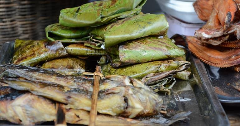 Fish and stuffed leaf pockets are offered for consumption at a street food stand in Phsar Nath Market in Battambang during the Cambodian tour.
