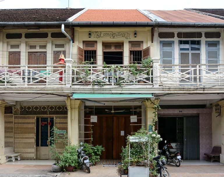 A yellow house with a balcony and wooden shutters in French colonial style characterizes the streetscape in Battambang, Cambodia.