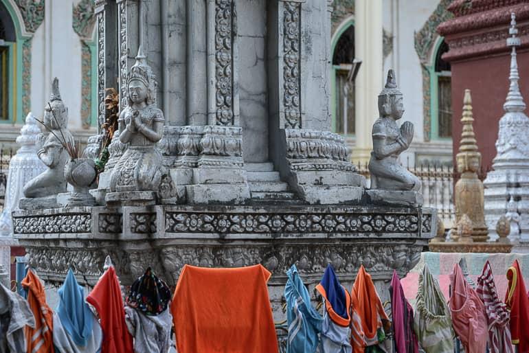 The stupas of the stone Buddha statue of Wat Dum Rey Sor in Battambang are hung with laundry for drying.