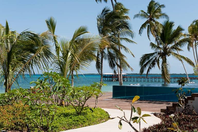 En el camino hacia la playa de The Residence Zanzibar en Tanzania, se ve una piscina de cristal, las palmeras se mecen suavemente en el viento.